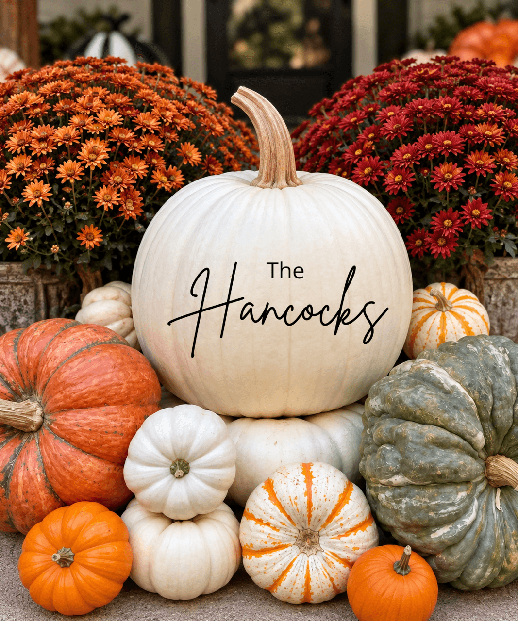 The Hancocks in black script on a white pumpkin among autumn pumpkins and orange and red mums